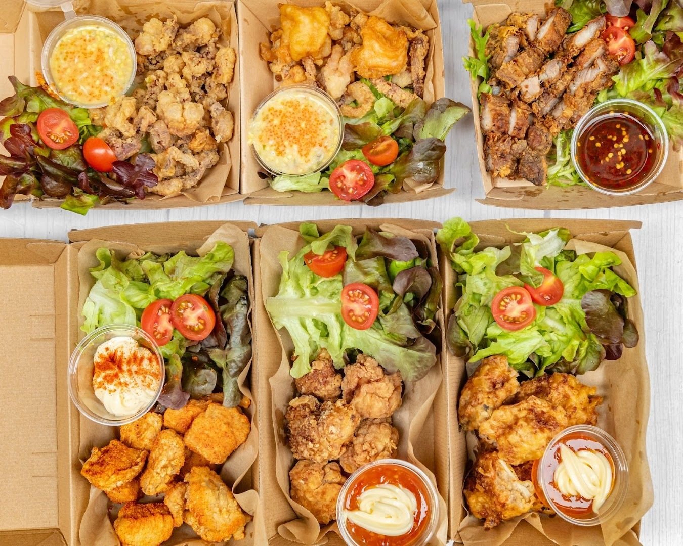 Takeaway boxes with fried Thai street food, salad, tomatoes, and sauces