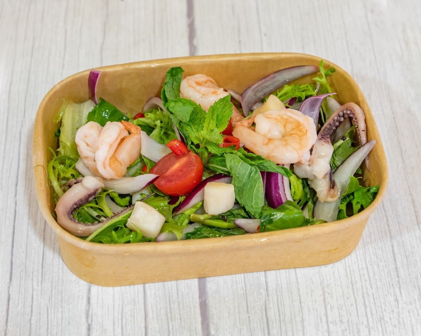 Seafood salad with prawns, squid, herbs, tomato, and red onion